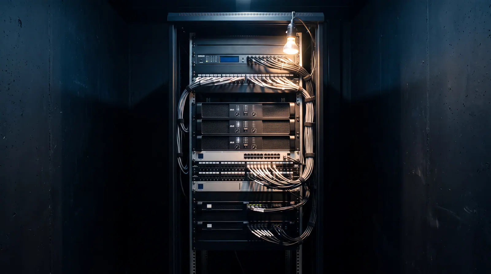 Design concept: a professional audio equipment rack with amplifiers, processing, and network hardware installed, cabling loom-laced and labeled.
